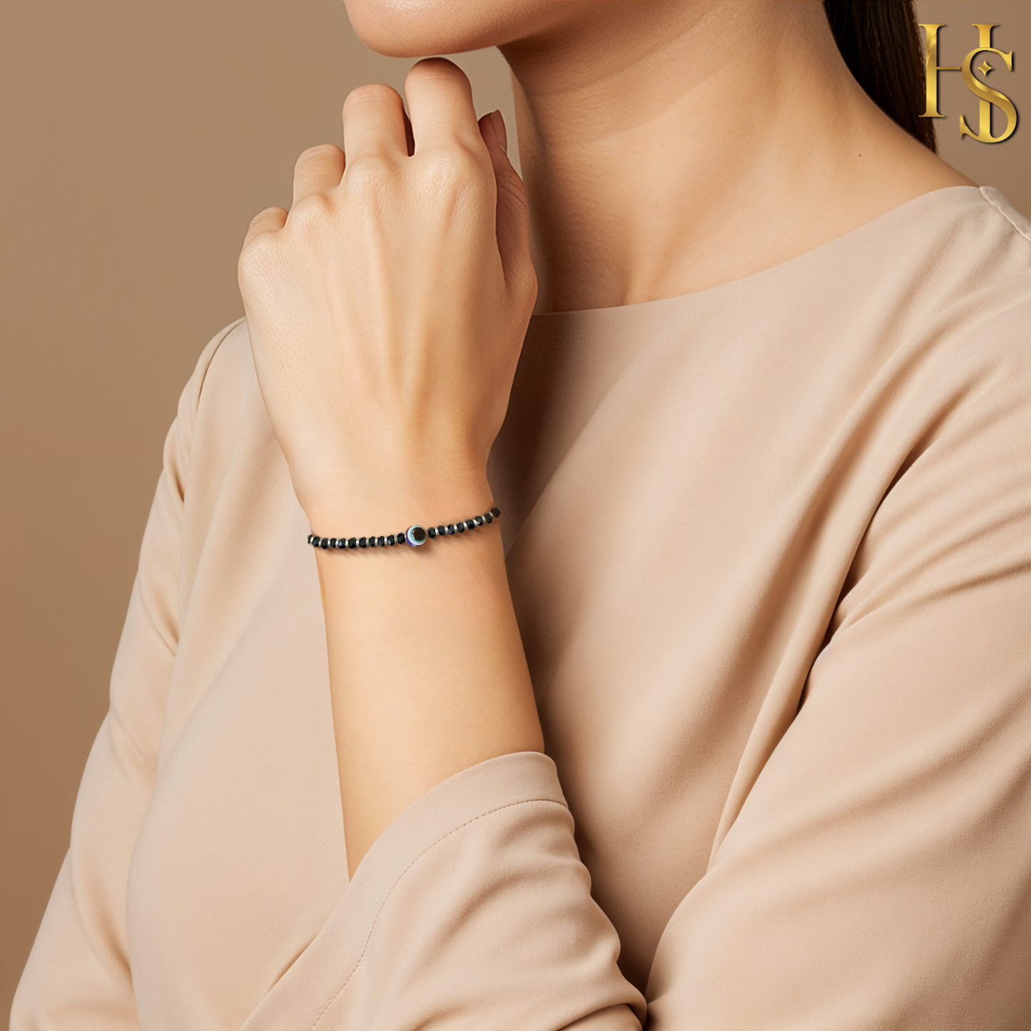 A sterling silver nazariya bracelet with black beads and a central evil eye charm worn on a woman's wrist against a beige background.