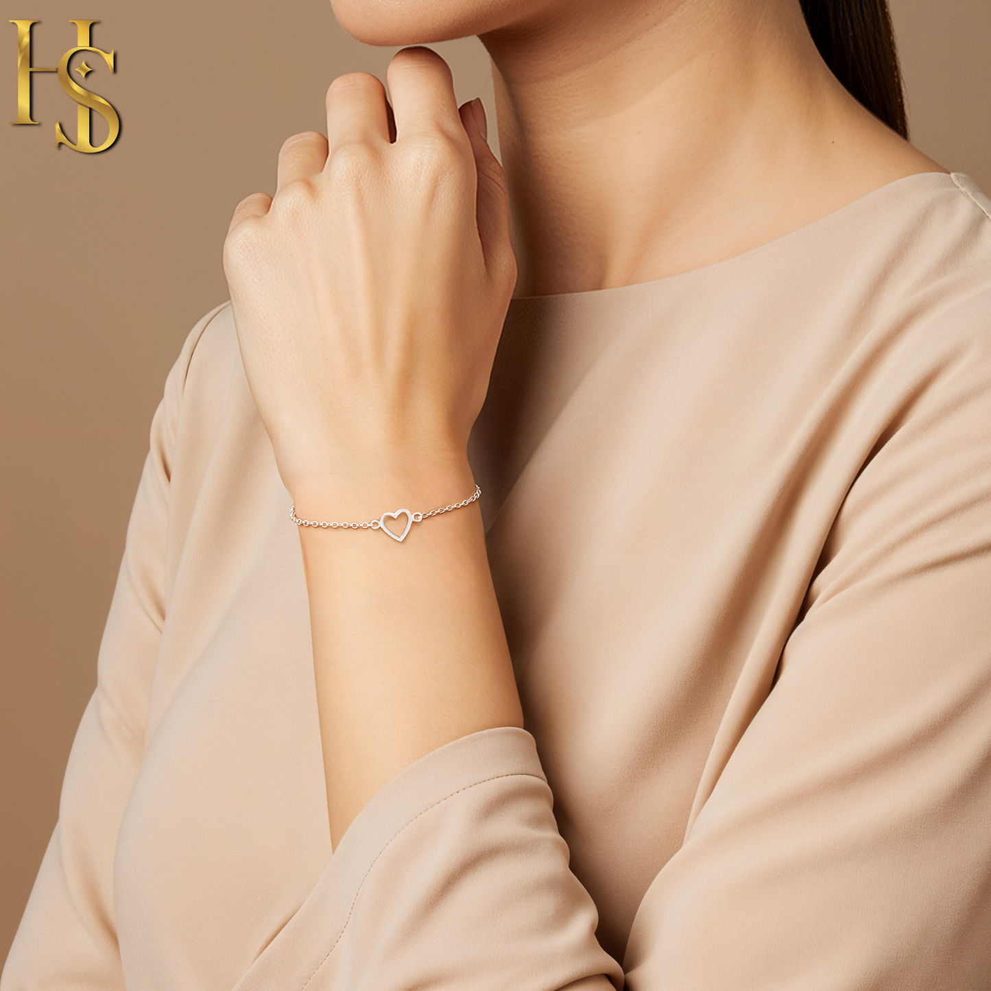 A delicate sterling silver chain bracelet with a central open heart motif, worn on a model's wrist against a neutral background.