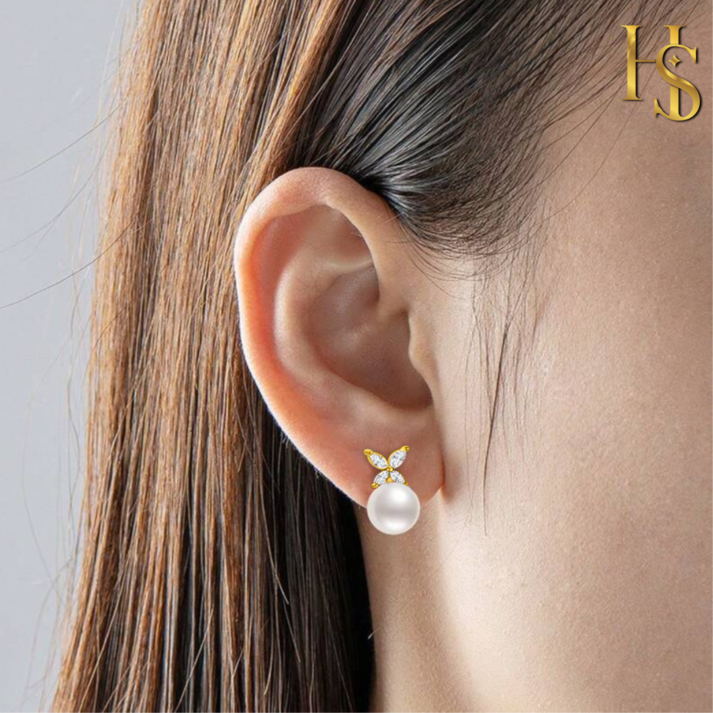 Gold-plated stud earrings with a marquise-cut American diamond butterfly on top of a round white pearl, worn on the ear.