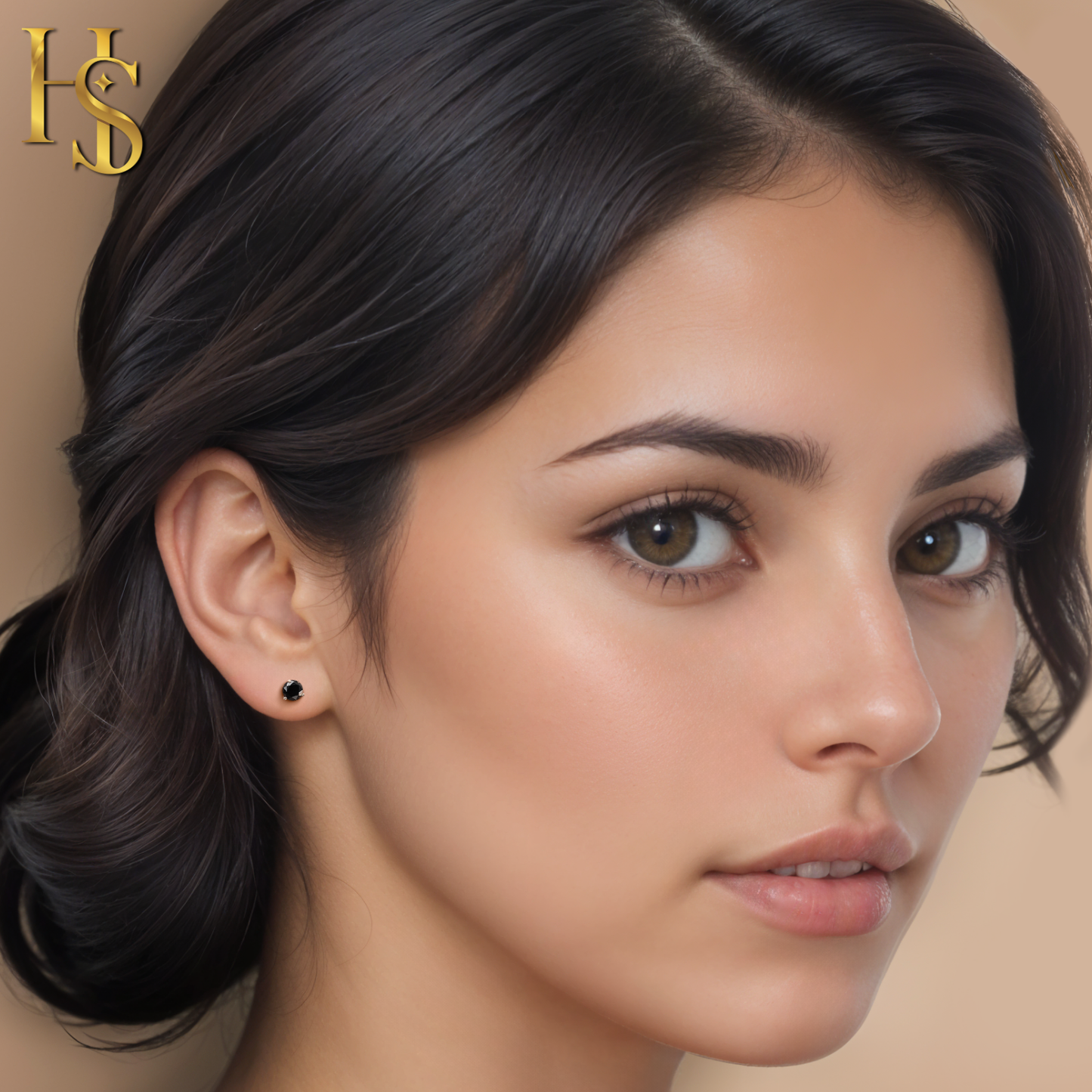 A small, round black solitaire stud earring in a sterling silver prong setting, worn on the ear of a model with dark hair.