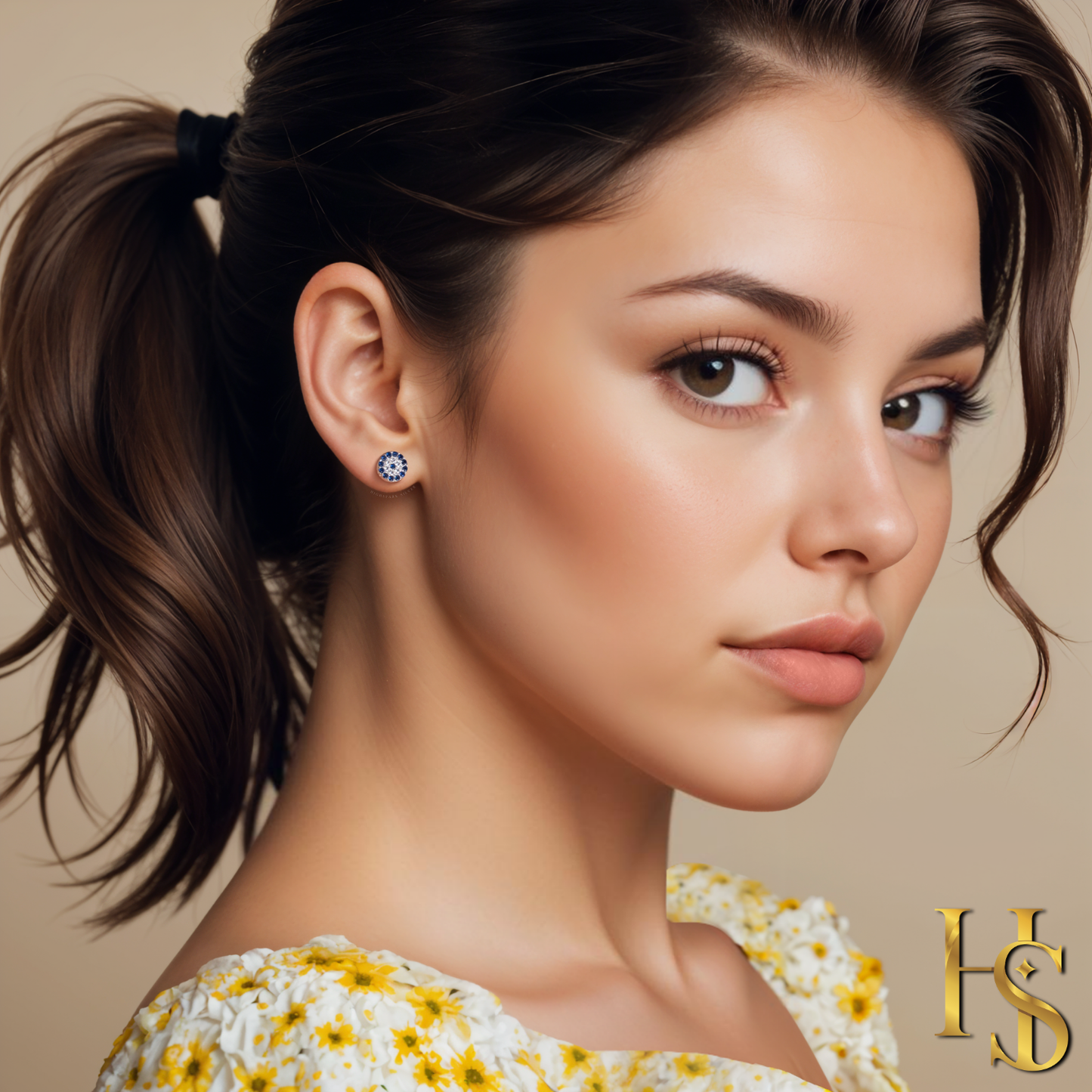 A round evil eye stud earring with blue and clear American diamonds in sterling silver, worn on the ear of a model.