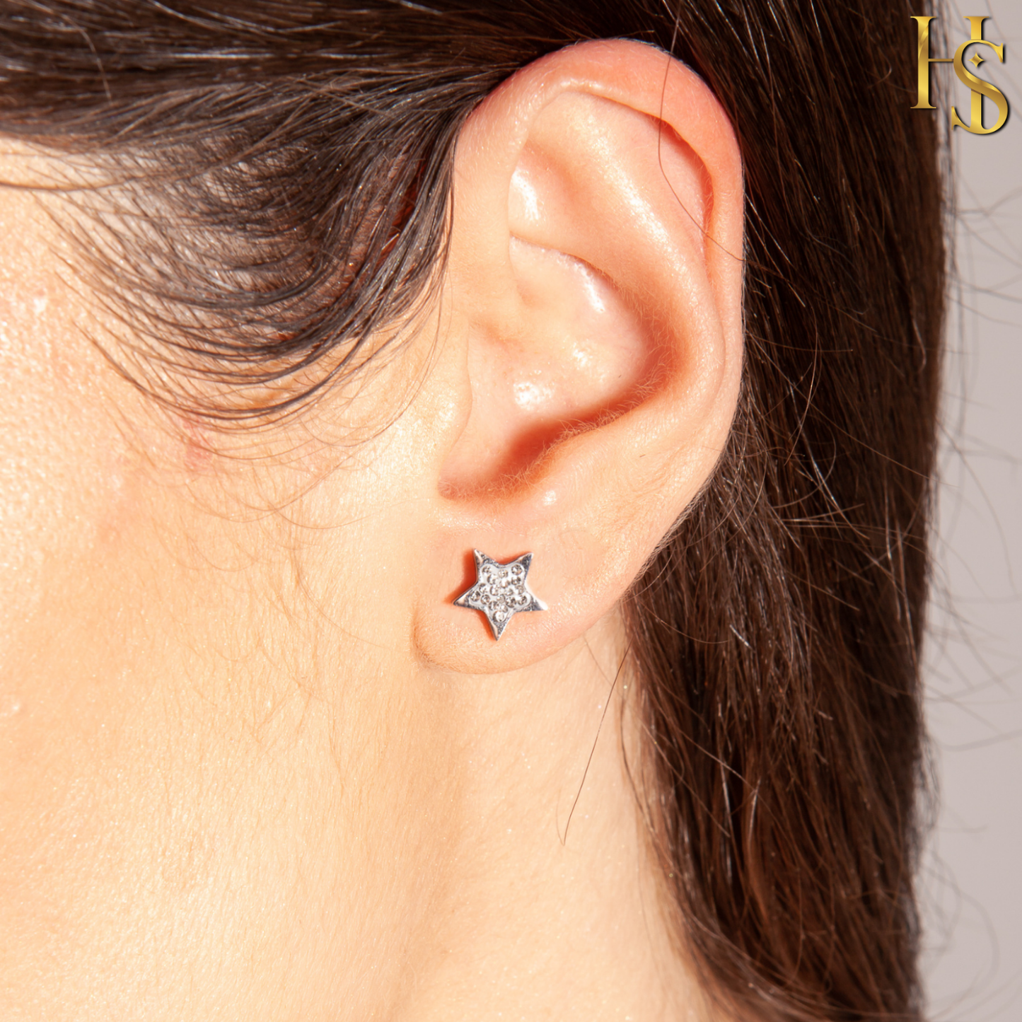 A small, star-shaped stud earring in sterling silver, pavé-set with tiny American diamonds, worn on the earlobe.