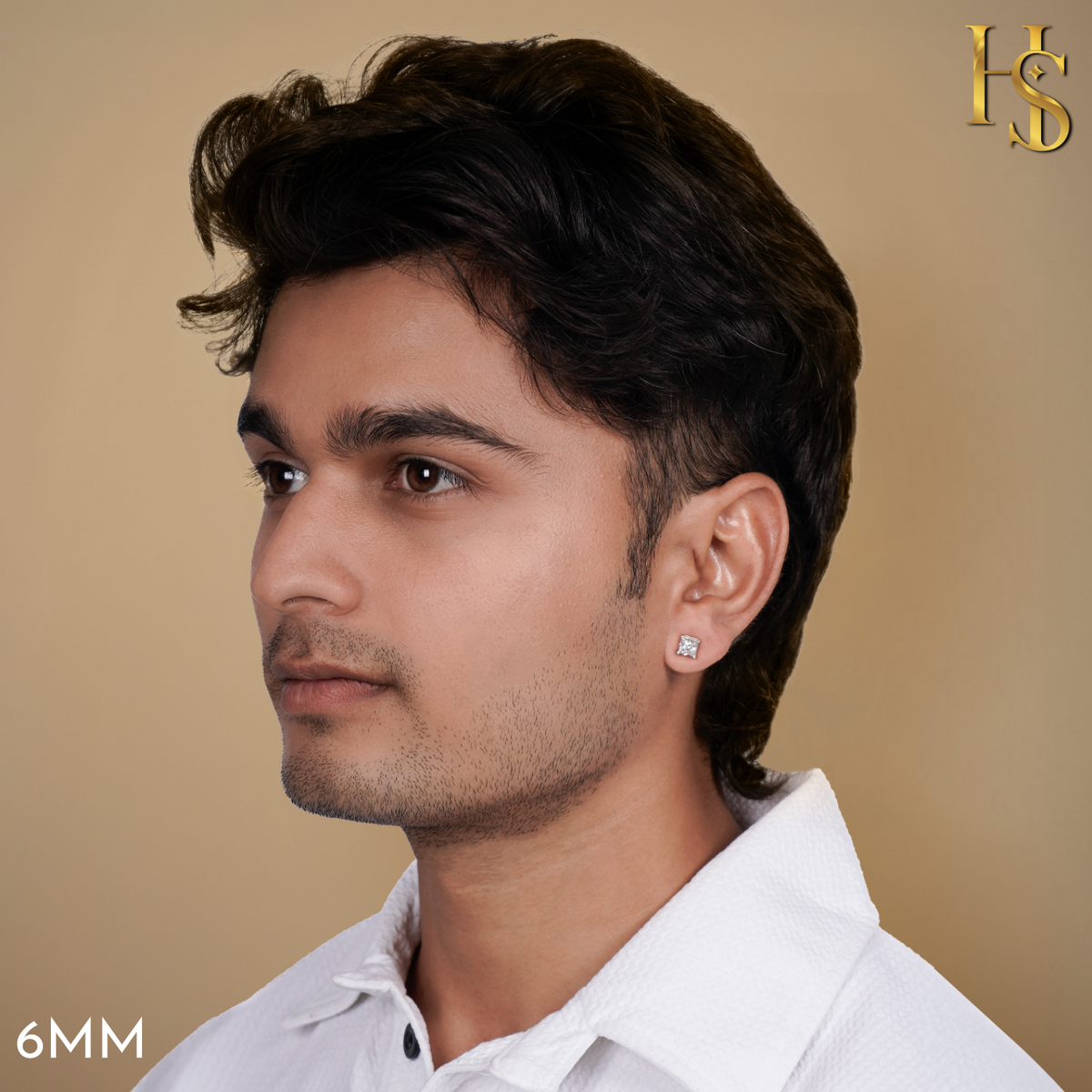 A square solitaire stud earring with a prong-set American diamond in sterling silver, worn on a man's ear against a beige background.