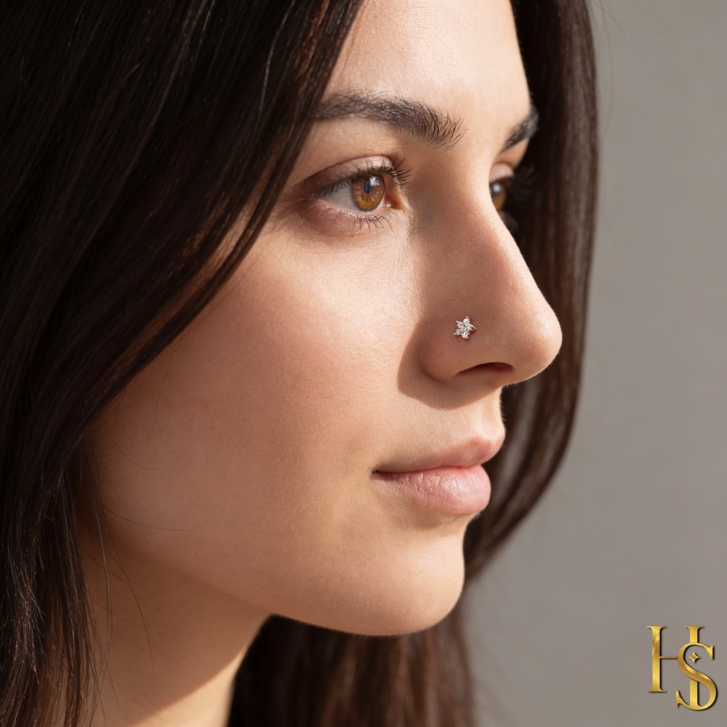 A sterling silver flower-shaped nose pin with prong-set American diamonds, shown worn on a model's nose in a profile view.