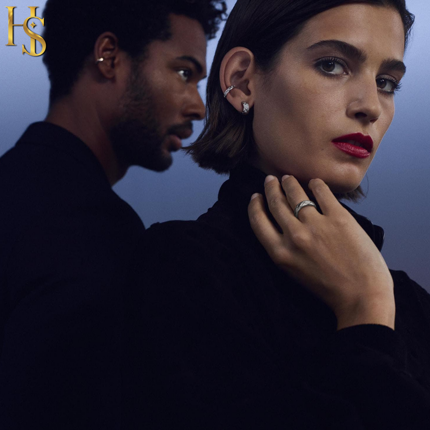 A woman wears a sterling silver ring with a criss-cross pattern on her finger, with a man wearing a matching ear cuff in the background.