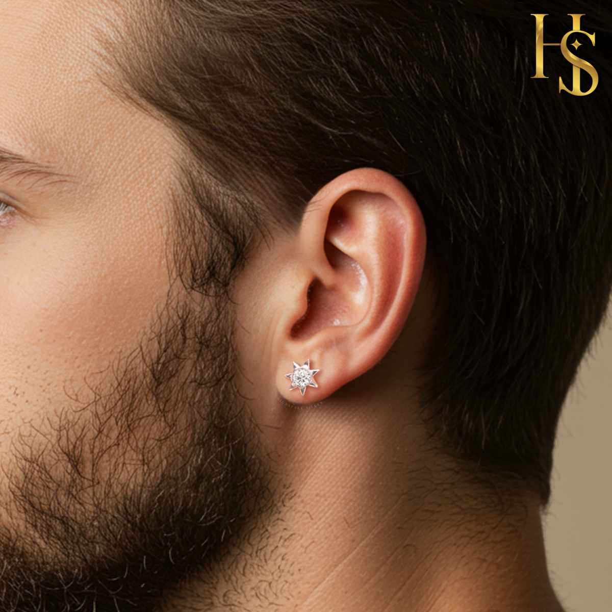 An eight-pointed star stud earring with a central American diamond, crafted in sterling silver and worn on a man's earlobe.