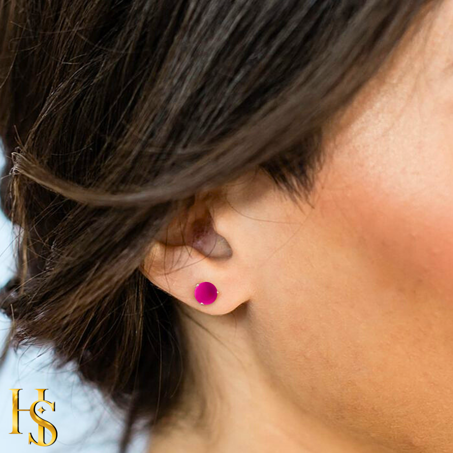 A small, round, hot pink jade gemstone stud earring in a sterling silver bezel setting, worn on the ear.