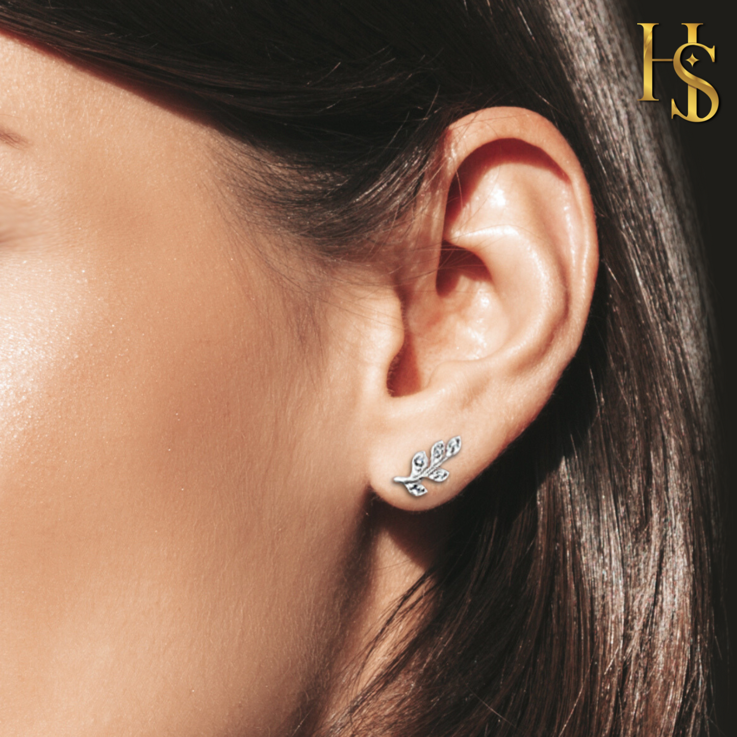 A sterling silver stud earring in a leaf motif with pave-set American diamonds, worn on the ear lobe.