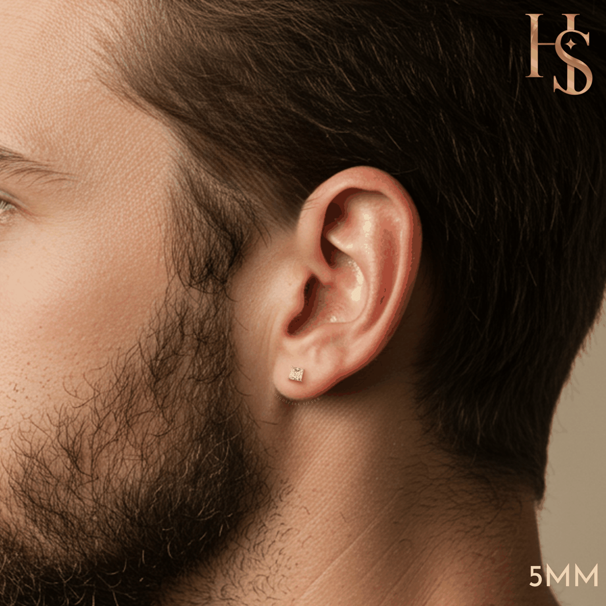 A square princess-cut American diamond solitaire stud earring in a four-prong sterling silver setting, worn on a man's ear.