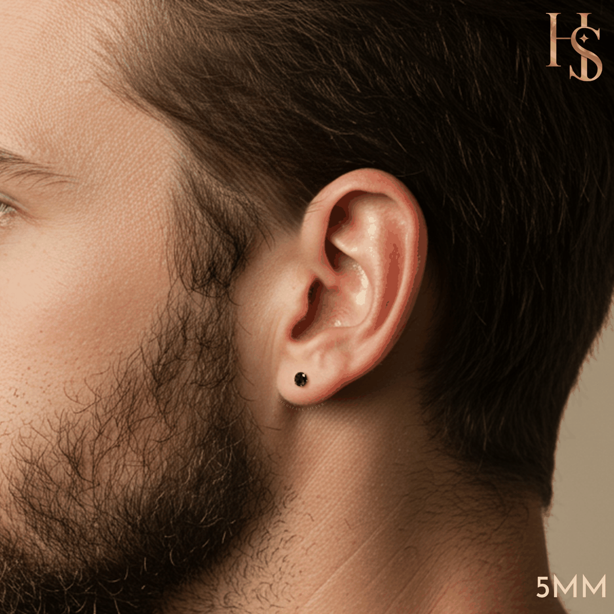 A small, round black solitaire stud earring in sterling silver worn on a man's earlobe.