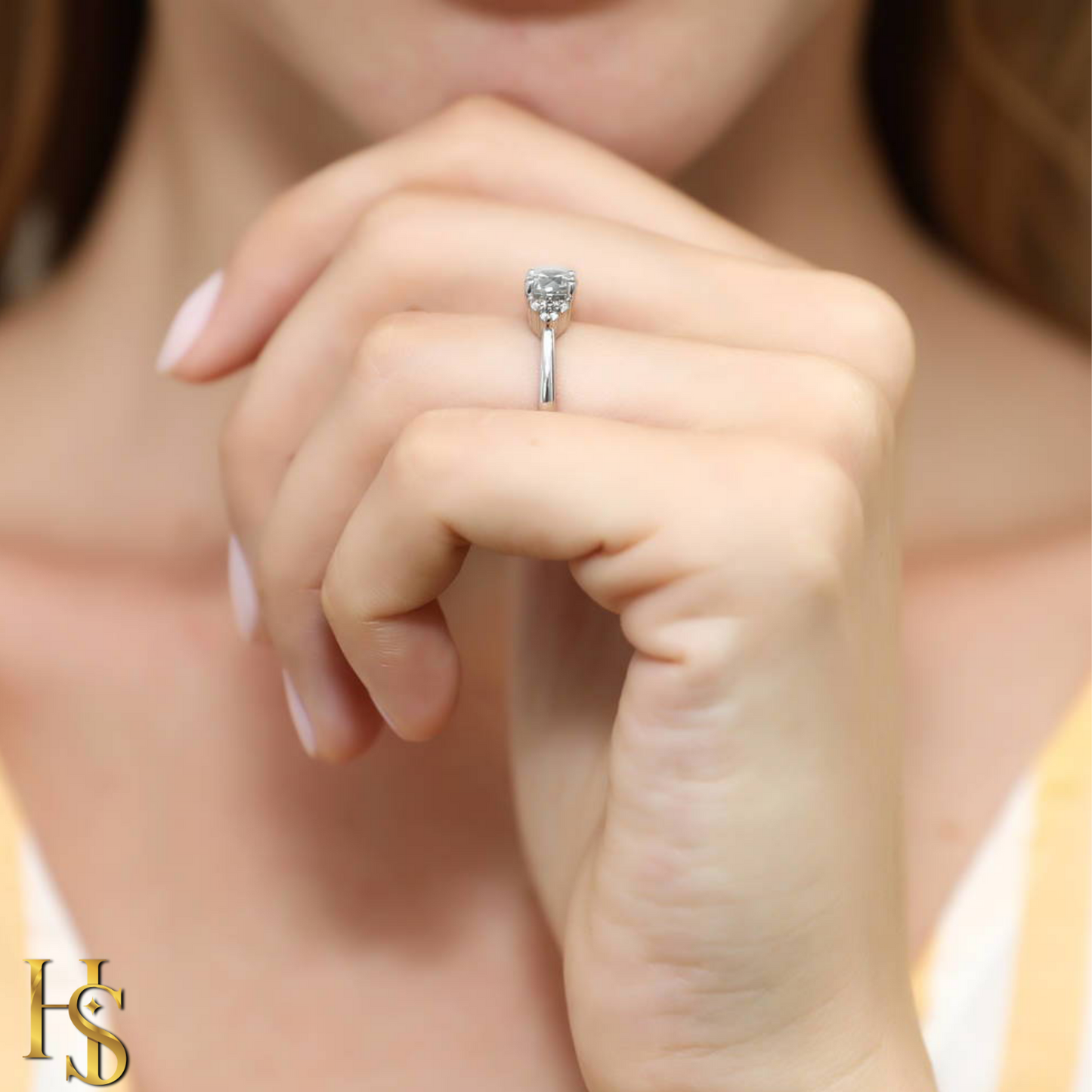 A sterling silver solitaire ring with a round American diamond in a six-prong setting, worn on a woman's hand.