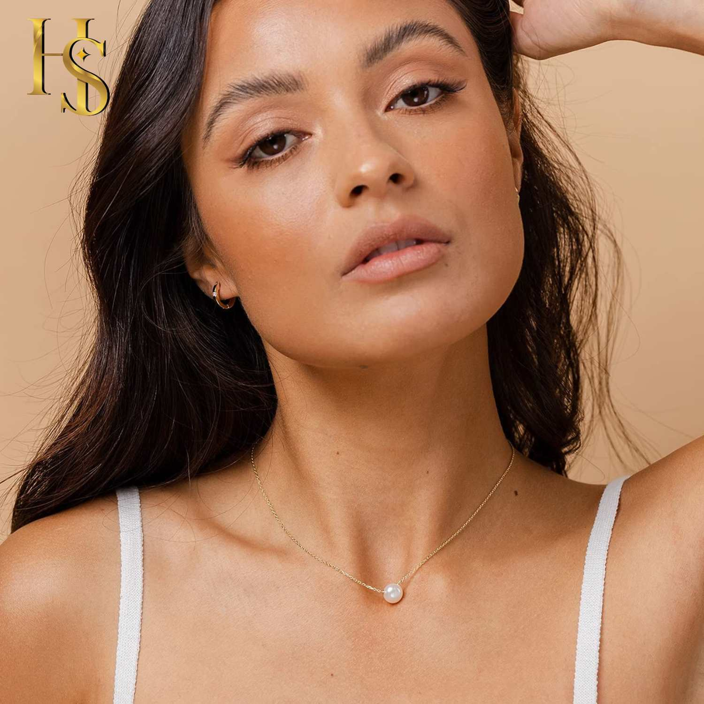 A gold-plated pendant necklace with a single round white pearl is worn on the neck of a model against a neutral background.