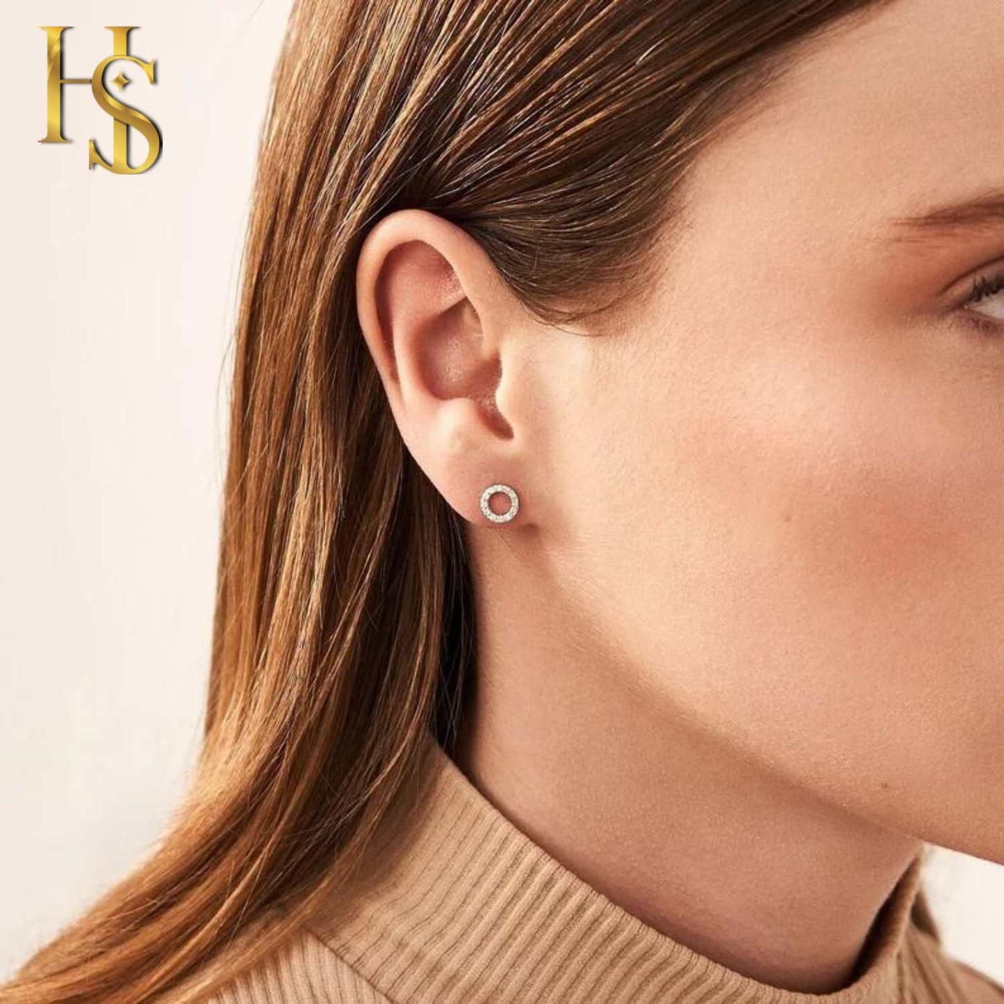A small, open circle stud earring paved with American diamonds in sterling silver, worn on the earlobe of a model.