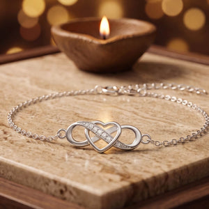 925 silver infinity heart chain bracelet with cubic zirconia, beside a lit diya - bracelets category