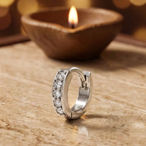 925 silver hinged nose ring hoop set with a row of cubic zirconia, beside a lit diya - nose rings category