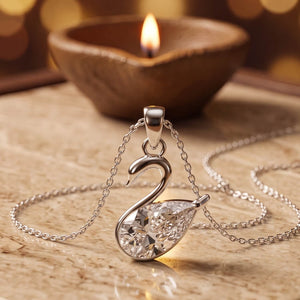 925 silver swan pendant with a pear-cut cubic zirconia on a chain, beside a lit diya - pendants category