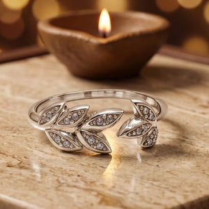 925 silver open leaf vine ring with pave cubic zirconia, beside a lit diya - rings category