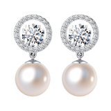 A pair of sterling silver drop earrings with a round pearl dangling from a halo of American diamonds, shown on a white background.
