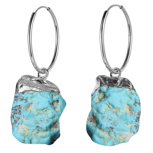 A pair of hoop earrings with raw, uncut turquoise gemstone charms in a sterling silver cap setting, shown on a white background.