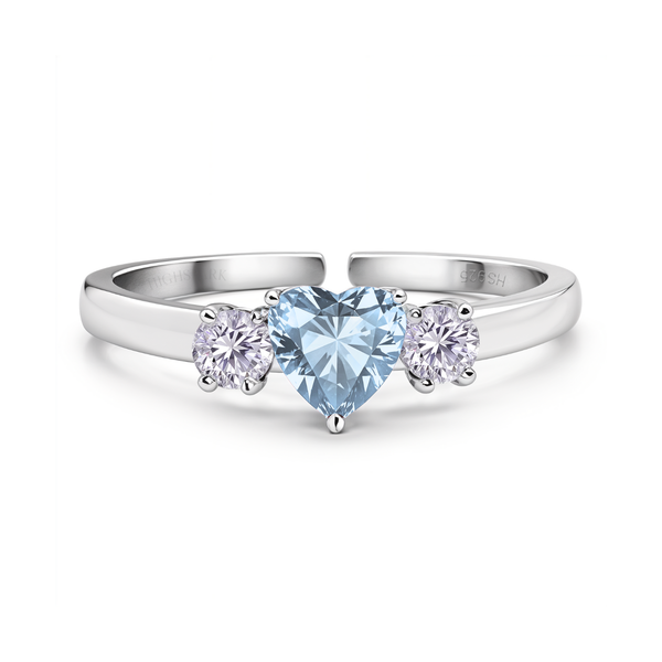 An adjustable sterling silver ring with a central heart-shaped light blue gemstone flanked by two round American diamonds in a prong.