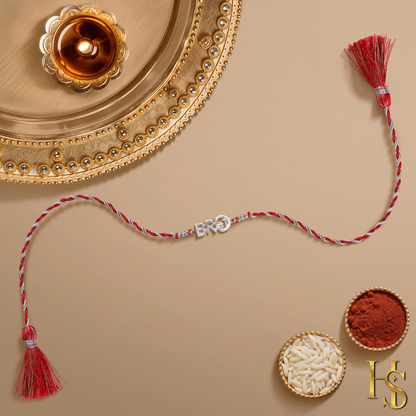 A 925 sterling silver rakhi for brother with a 'BRO' hashtag centerpiece on a red and silver twisted thread, shown with a pooja thali.