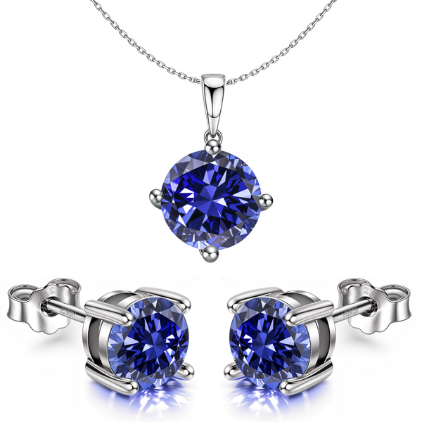A pendant and stud earring set with round tanzanite-blue stones in a four-prong setting, made of sterling silver on a white background.
