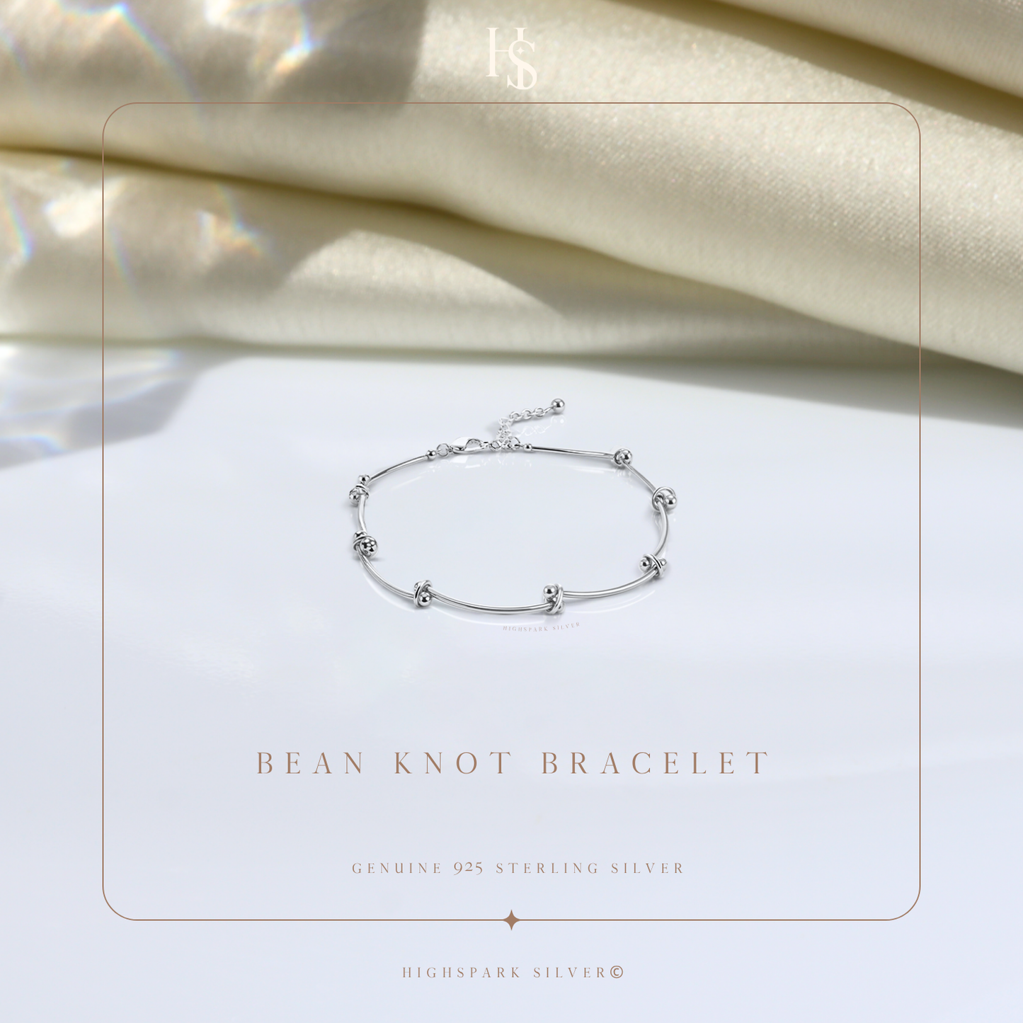 A sterling silver bracelet with polished bean-shaped knots styled on a white surface with draped cream fabric in the background.