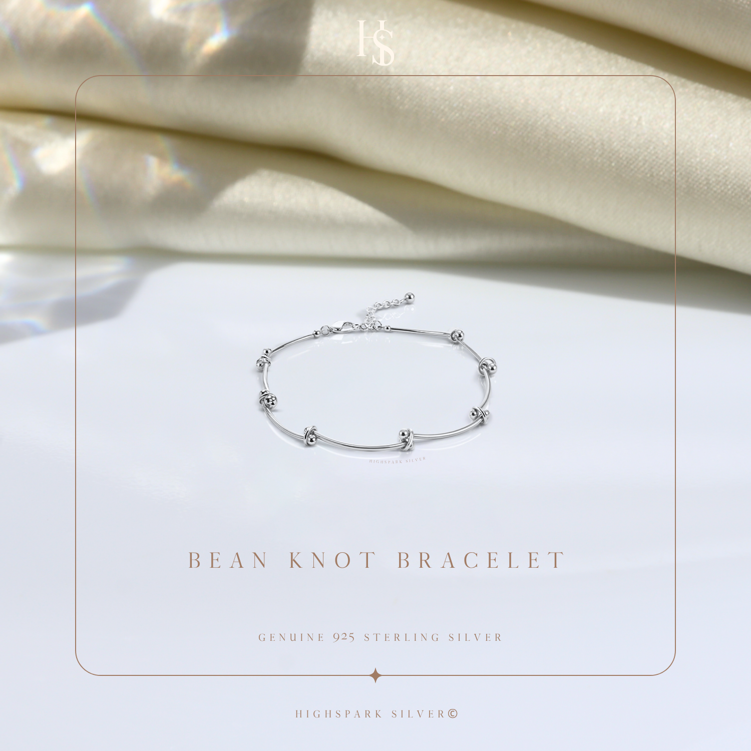 A sterling silver bracelet with polished bean-shaped knots styled on a white surface with draped cream fabric in the background.