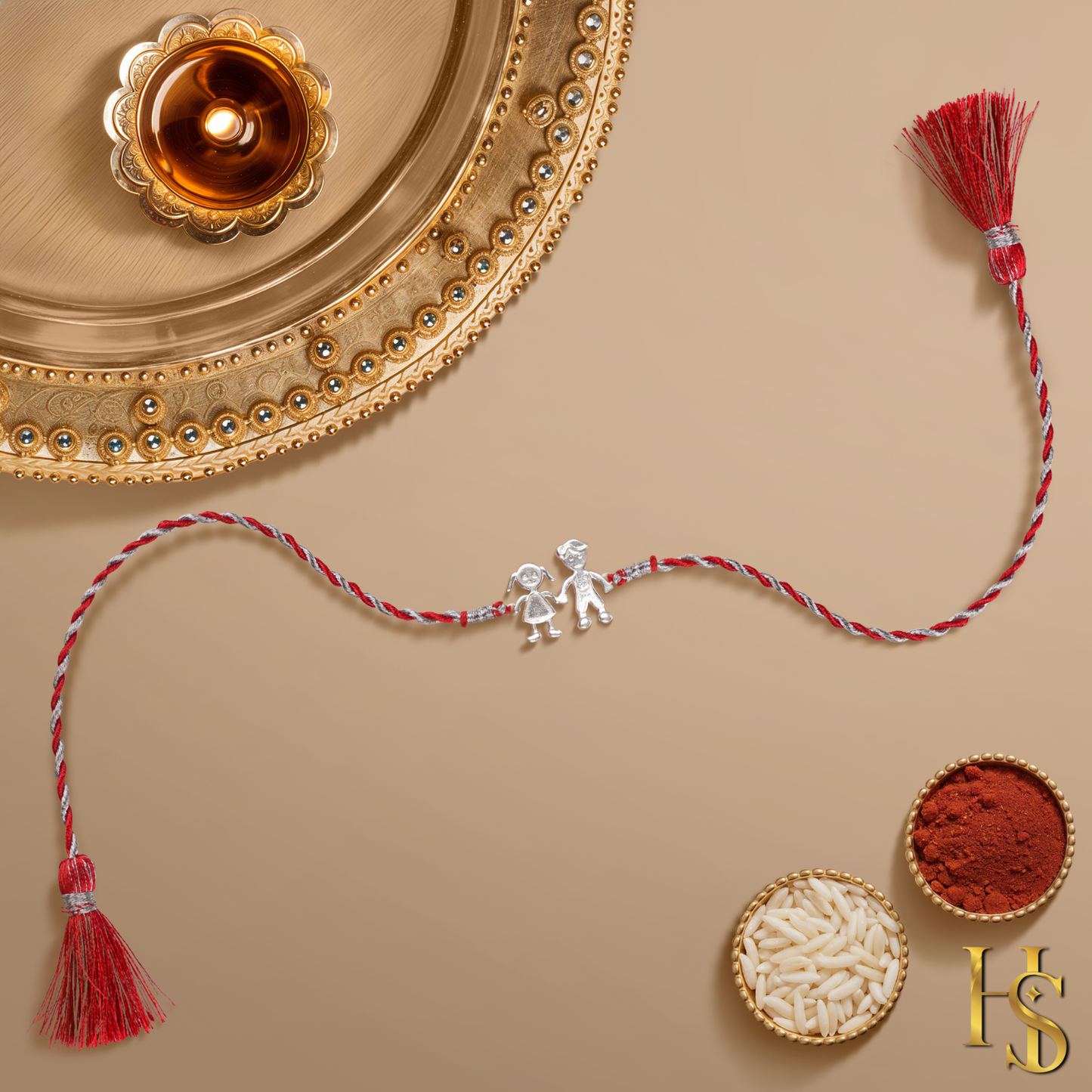 A 925 sterling silver rakhi for a brother with a brother-sister motif on a red and silver thread, styled with a puja thali.