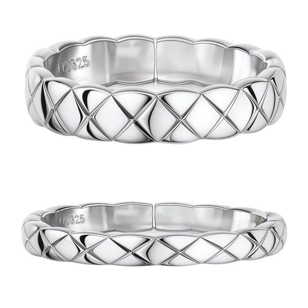 A pair of sterling silver couple rings, one wider and one narrower, with a carved criss-cross quilted pattern, on a white background.