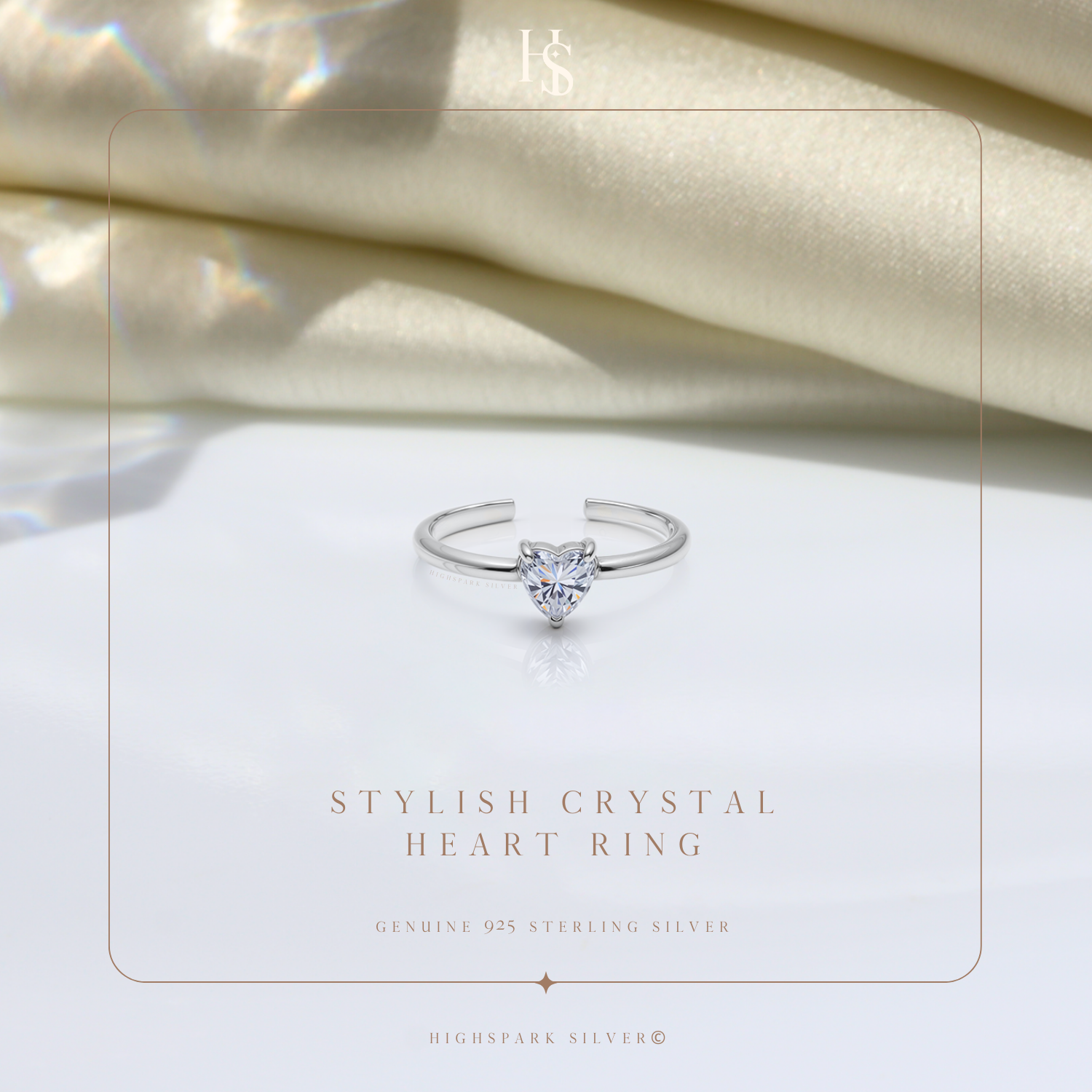 An adjustable sterling silver ring with a solitaire heart-shaped American diamond, styled on a white surface with draped cream satin fabric.