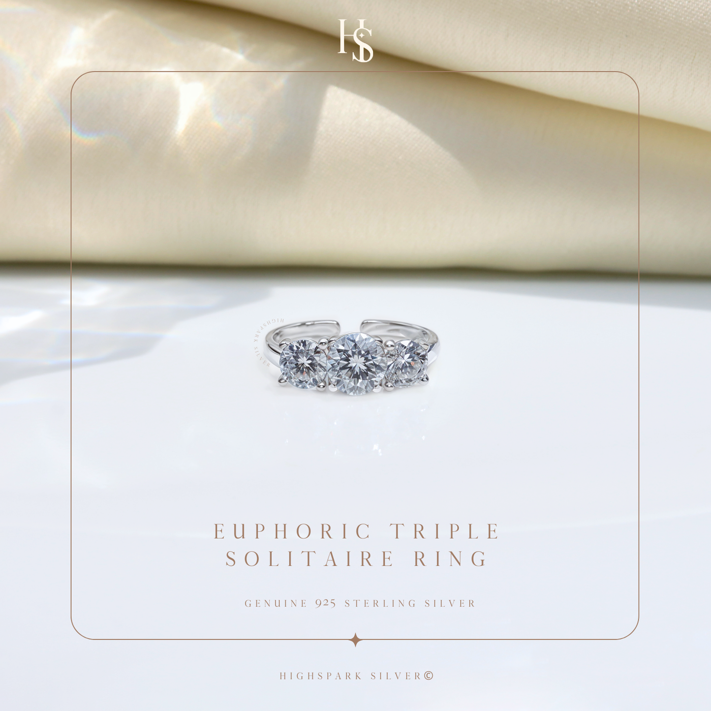 An adjustable sterling silver ring with three round American diamonds in a prong setting, styled on a white surface with draped cream satin.