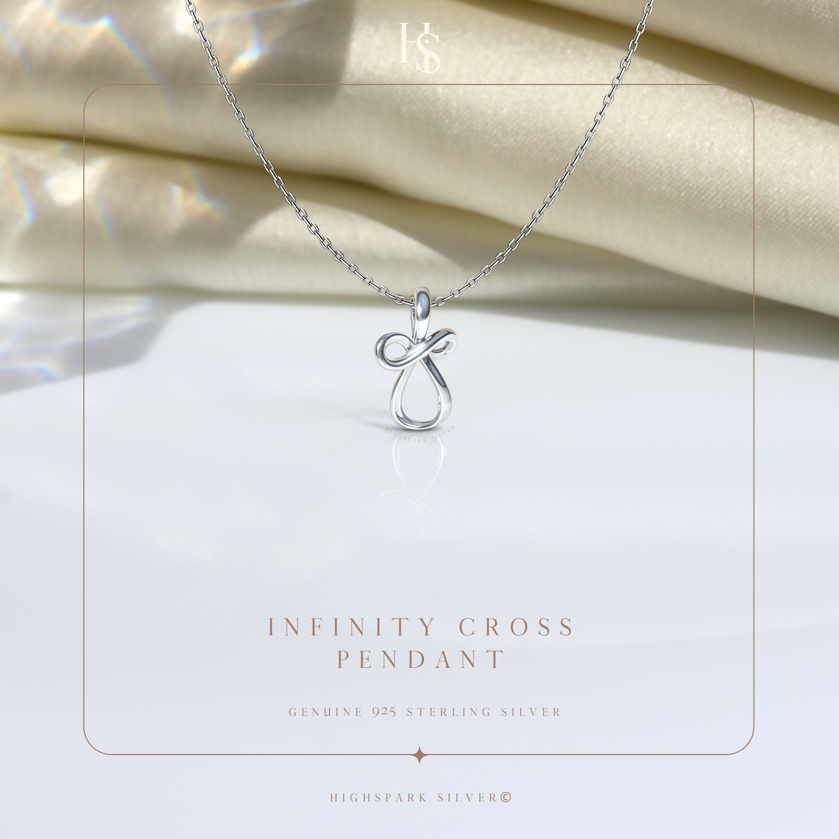 A sterling silver pendant necklace with an infinity cross motif, styled on a white surface with draped cream satin in the background.