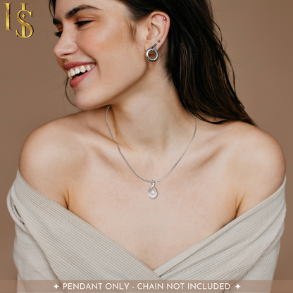 A smiling woman wears an infinity loop sterling silver pendant with a single pearl on a snake chain against her collarbone.