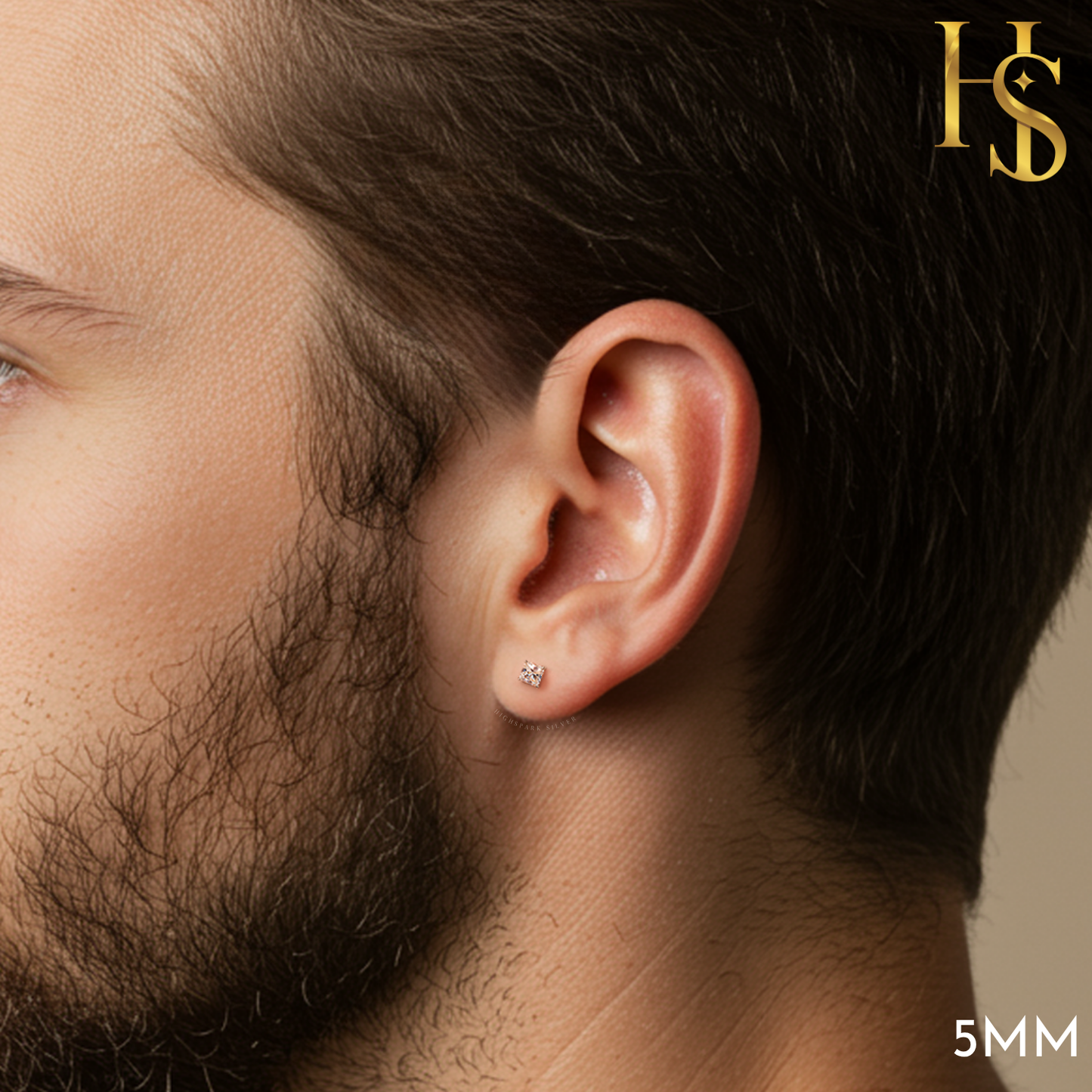 A small, round solitaire American diamond stud earring in a four-prong sterling silver setting, worn on a man's ear.