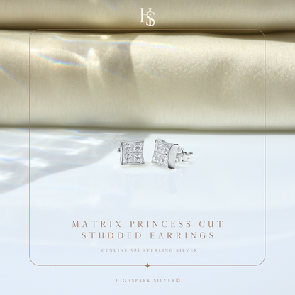 A pair of sterling silver stud earrings with four princess-cut American diamonds each, styled on a white surface with beige fabric.