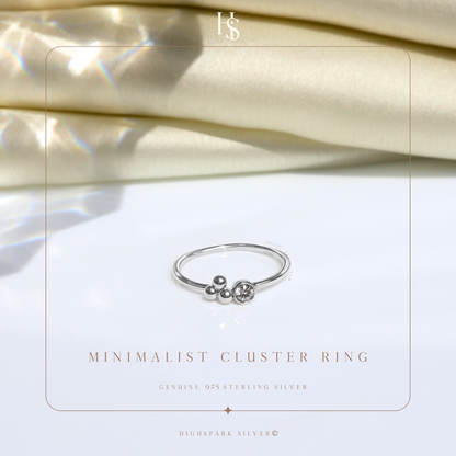 A minimalist sterling silver ring with a cluster of silver beads and a single bezel-set American diamond.