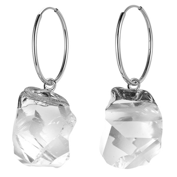 A pair of sterling silver hoop earrings with dangling, raw-cut, clear quartz gemstone charms on a plain white background.