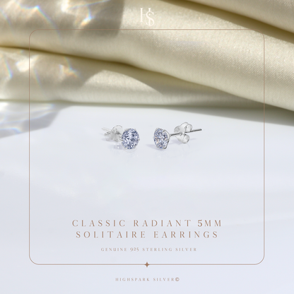 A pair of sterling silver stud earrings with round American diamond solitaires in a six-prong setting.
