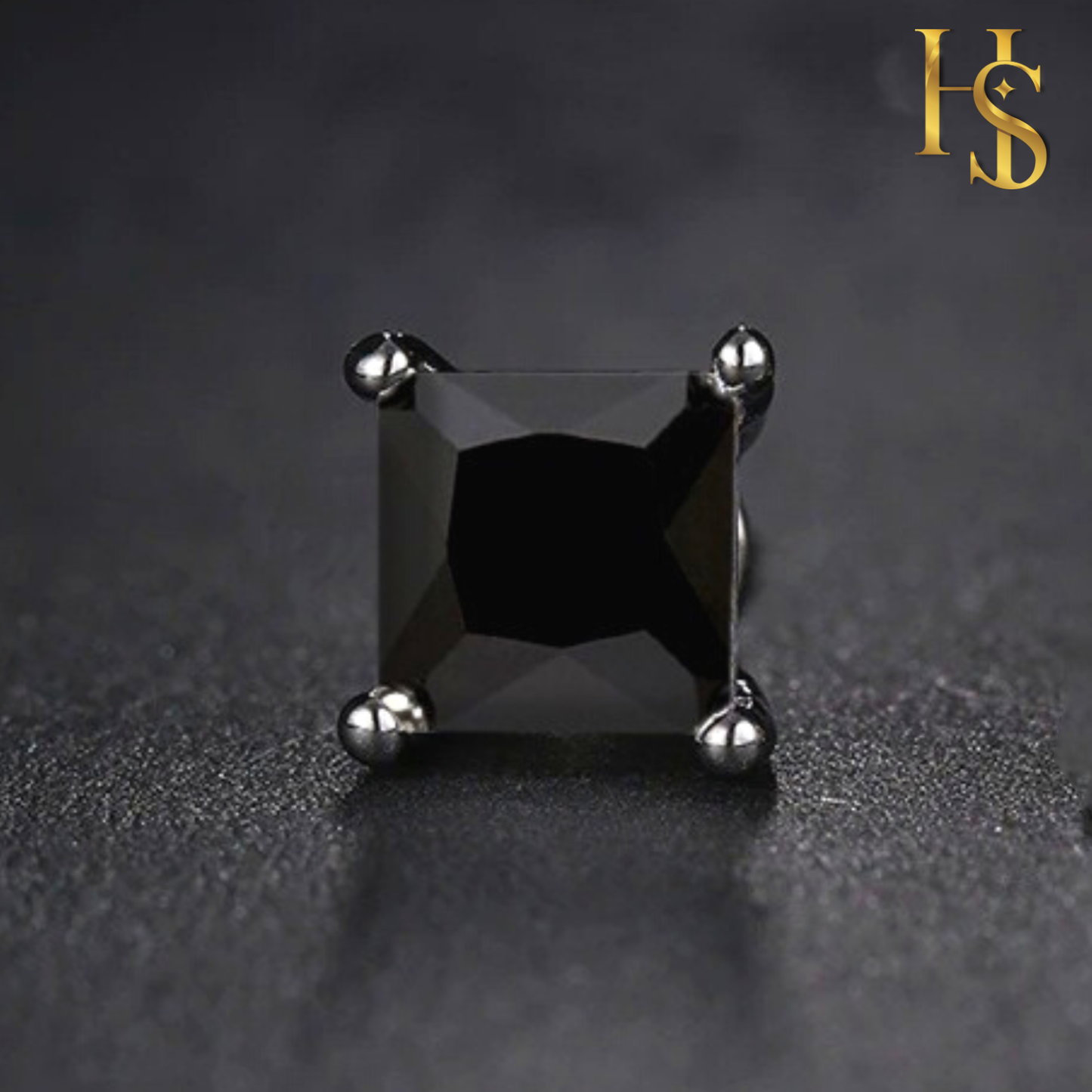 A single stud earring with a square-cut black stone in a four-prong sterling silver setting, shown on a dark textured surface.