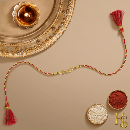 A 925 sterling silver rakhi for brother with a gold-finish 'bro' and heart motif on a red and gold thread, shown with a pooja thali.