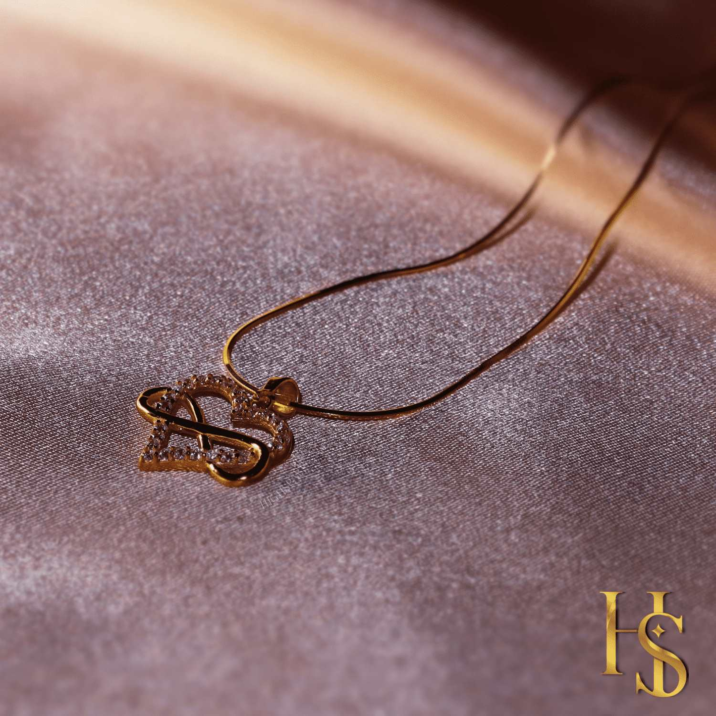 A gold-plated pendant necklace with an infinity symbol woven through a heart, studded with American diamonds.