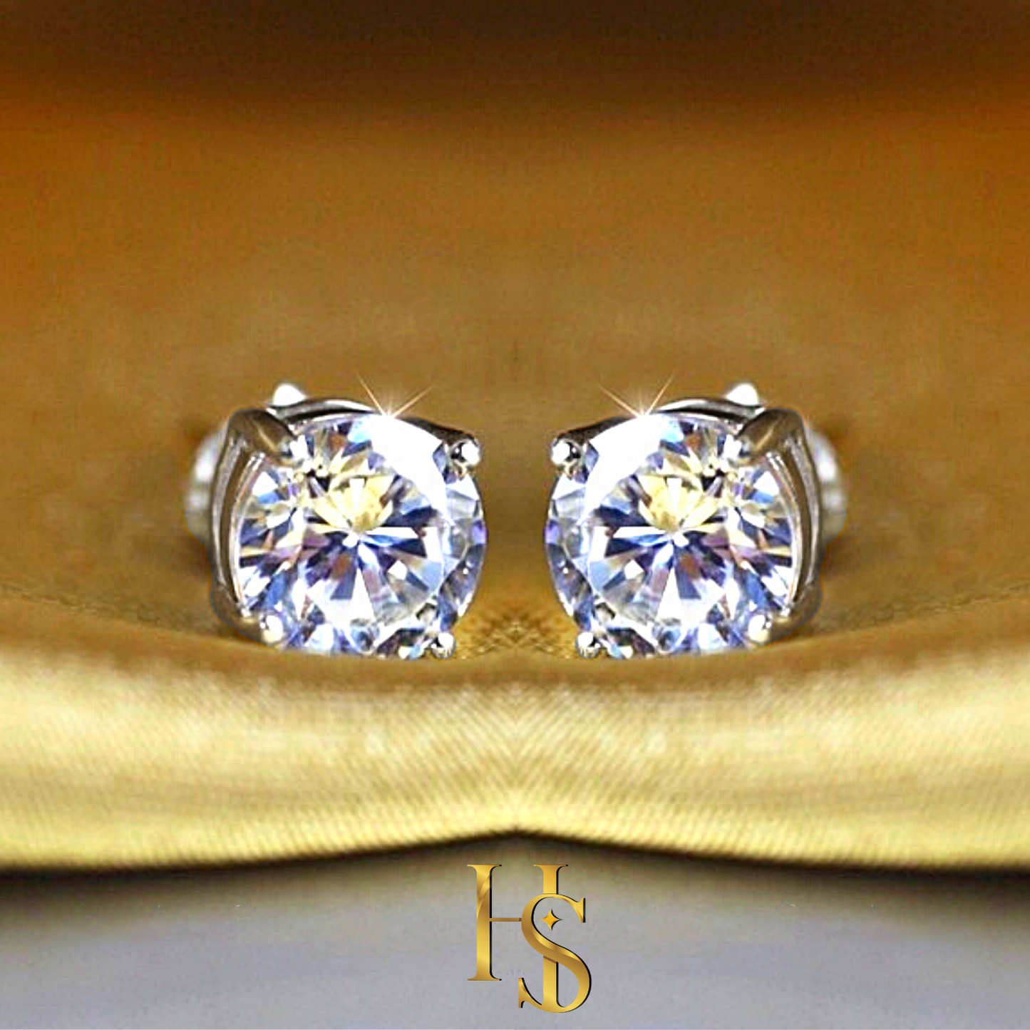 A pair of solitaire stud earrings with round American diamonds in a four-prong setting, styled on a folded golden-yellow satin fabric.