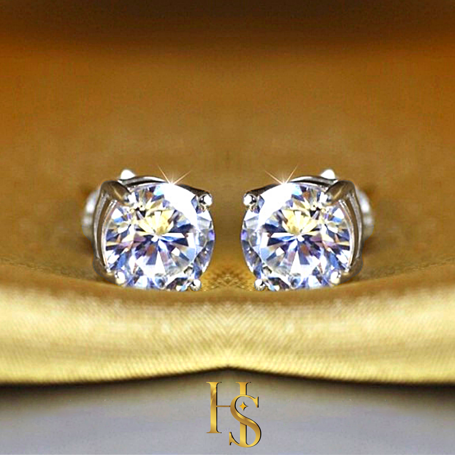 A pair of solitaire stud earrings with round American diamonds in a four-prong setting, styled on a folded golden-yellow satin fabric.