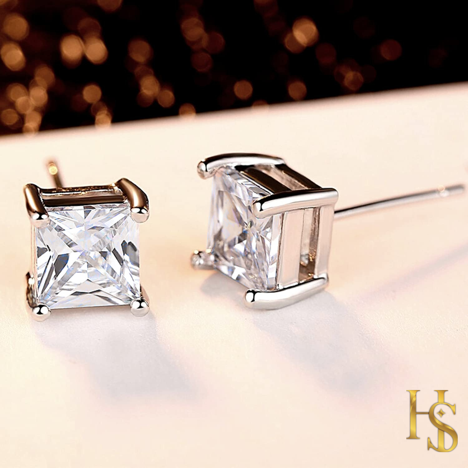 A pair of sterling silver stud earrings with princess-cut American diamonds in a four-prong setting.