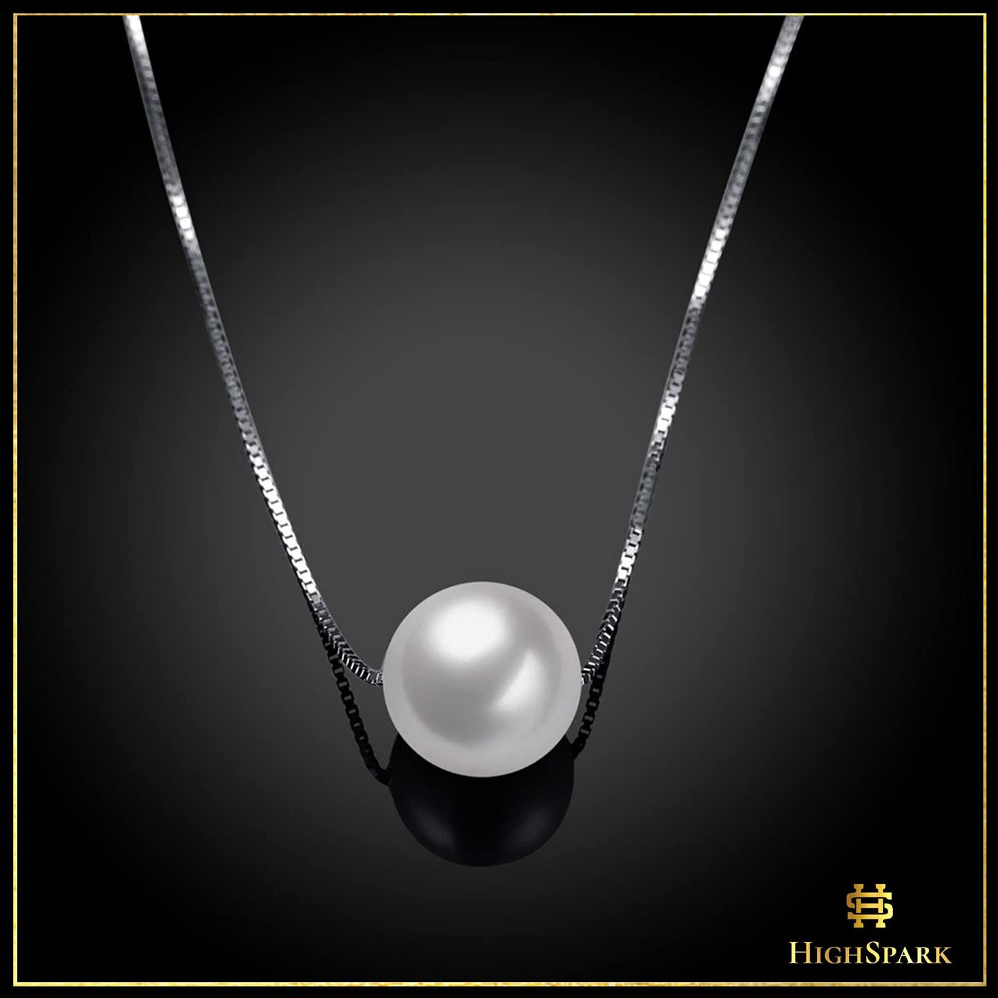 A single white pearl pendant necklace on a sterling silver box chain, styled on a reflective black surface.