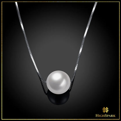 A single white pearl pendant necklace on a sterling silver box chain, styled on a reflective black surface.